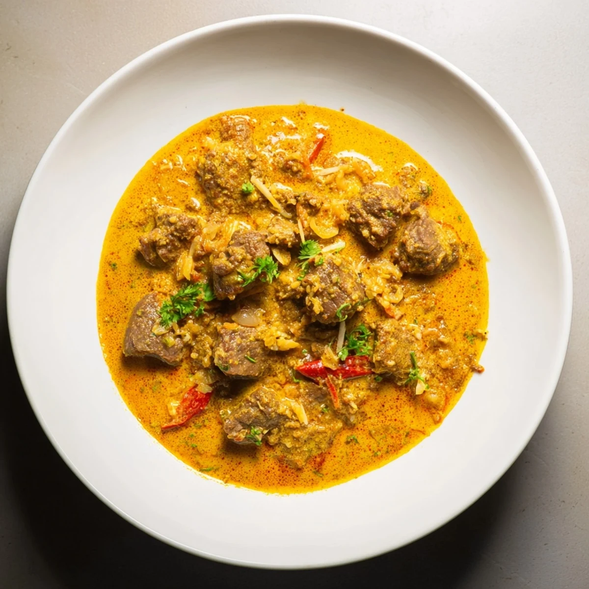 Close-up view of a steaming bowl of beef curry, richly flavored and aromatic.
