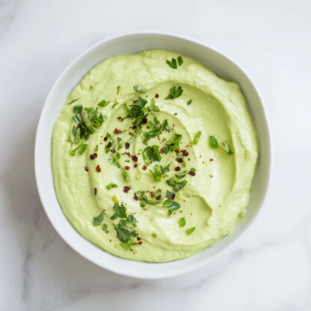 This vibrant bowl of Creamy Avocado Lime Dressing features a gorgeous texture, and suggests a cool, refreshing flavor.