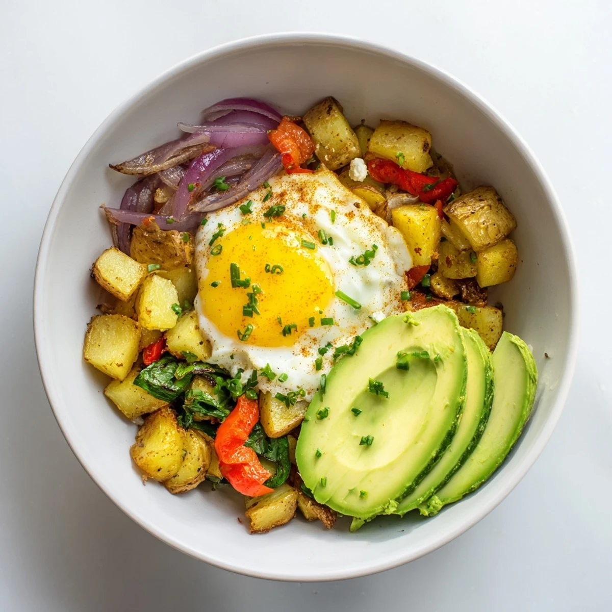 Savory breakfast bowl with golden roasted potatoes, topped with creamy avocado and feta.