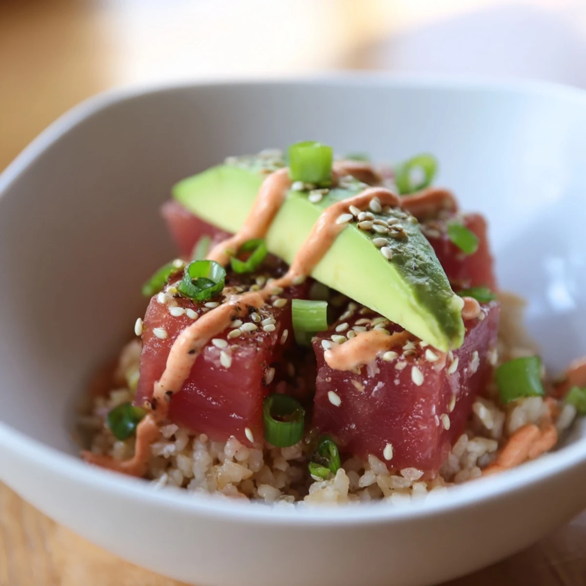 A colorful Spicy Tuna Poke Bowl with Sriracha Mayo topped with avocado and cucumber slices.