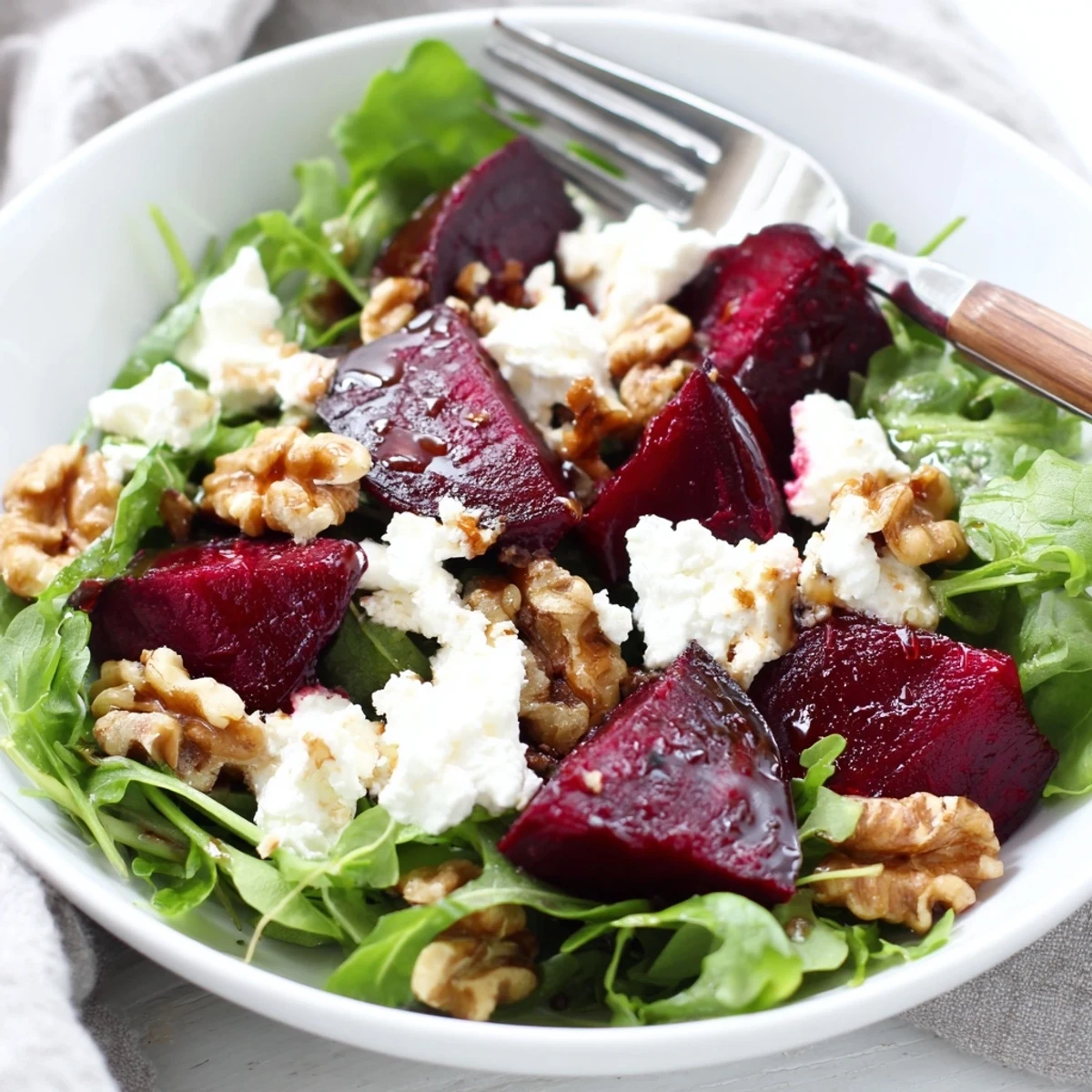 A close-up of Roasted Beet and Goat Cheese Salad with Walnuts, showing glistening beets and crumbled goat cheese on greens.