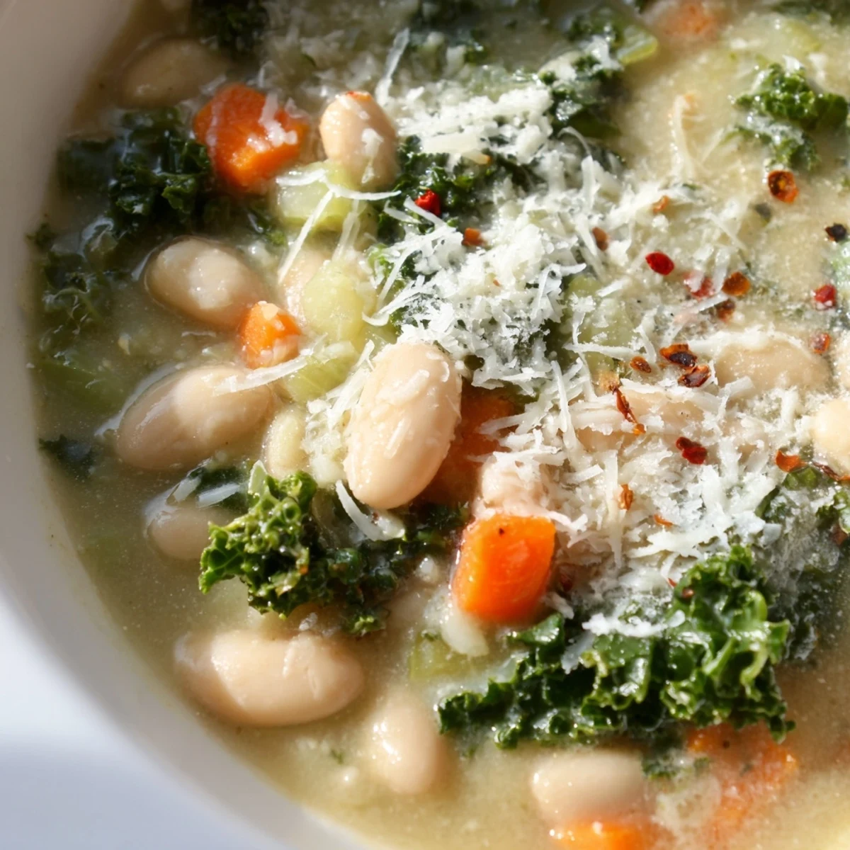 Close-up of Creamy White Bean and Kale Tuscany Soup showing tender kale and a silky, herb-scented broth.