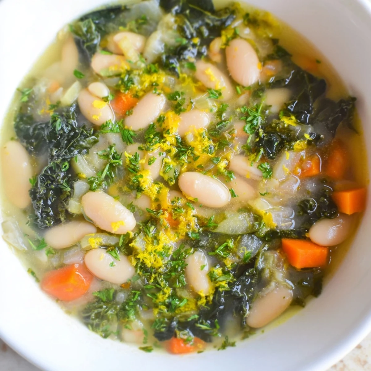 A warm bowl of White Bean and Kale Soup with Lemon Zest, garnished with fresh parsley and served with crusty bread.