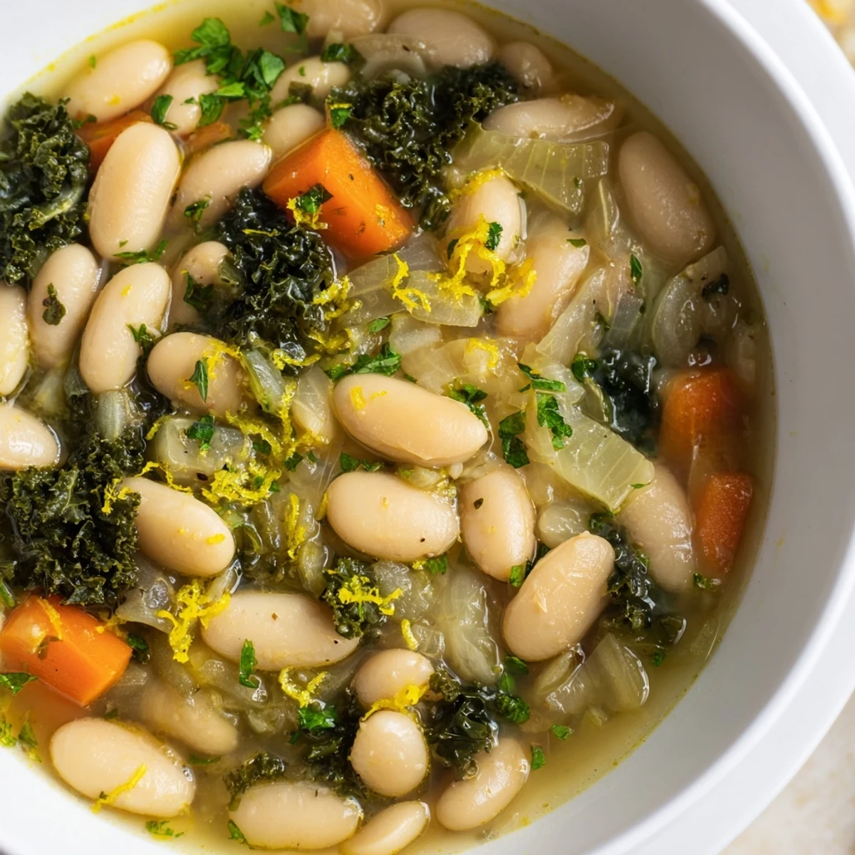 Steaming White Bean and Kale Soup with Lemon Zest features tender beans, chopped kale, and bright lemon zest on a rustic table.