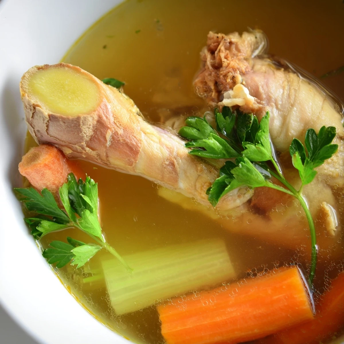 Fresh ginger slices and shredded chicken float in the nourishing Homemade Chicken Bone Broth.