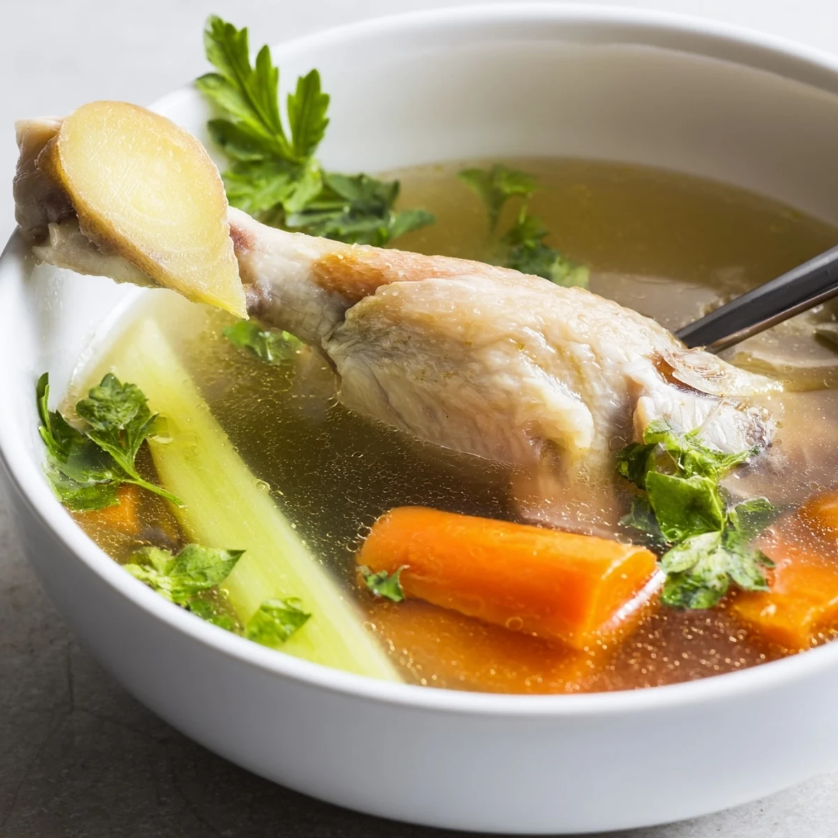 Homemade Chicken Bone Broth with Ginger served in a rustic mug near bread.