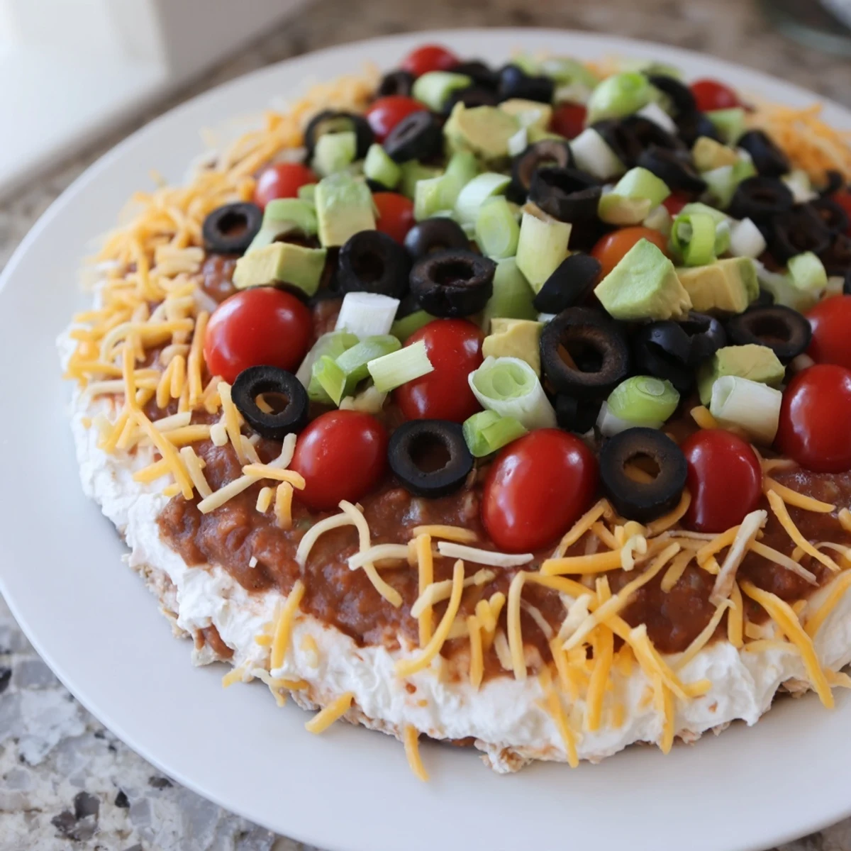 Freshly prepared Ultimate Layered Taco Dip with a rainbow of toppings and tortilla chips, perfect for a party.