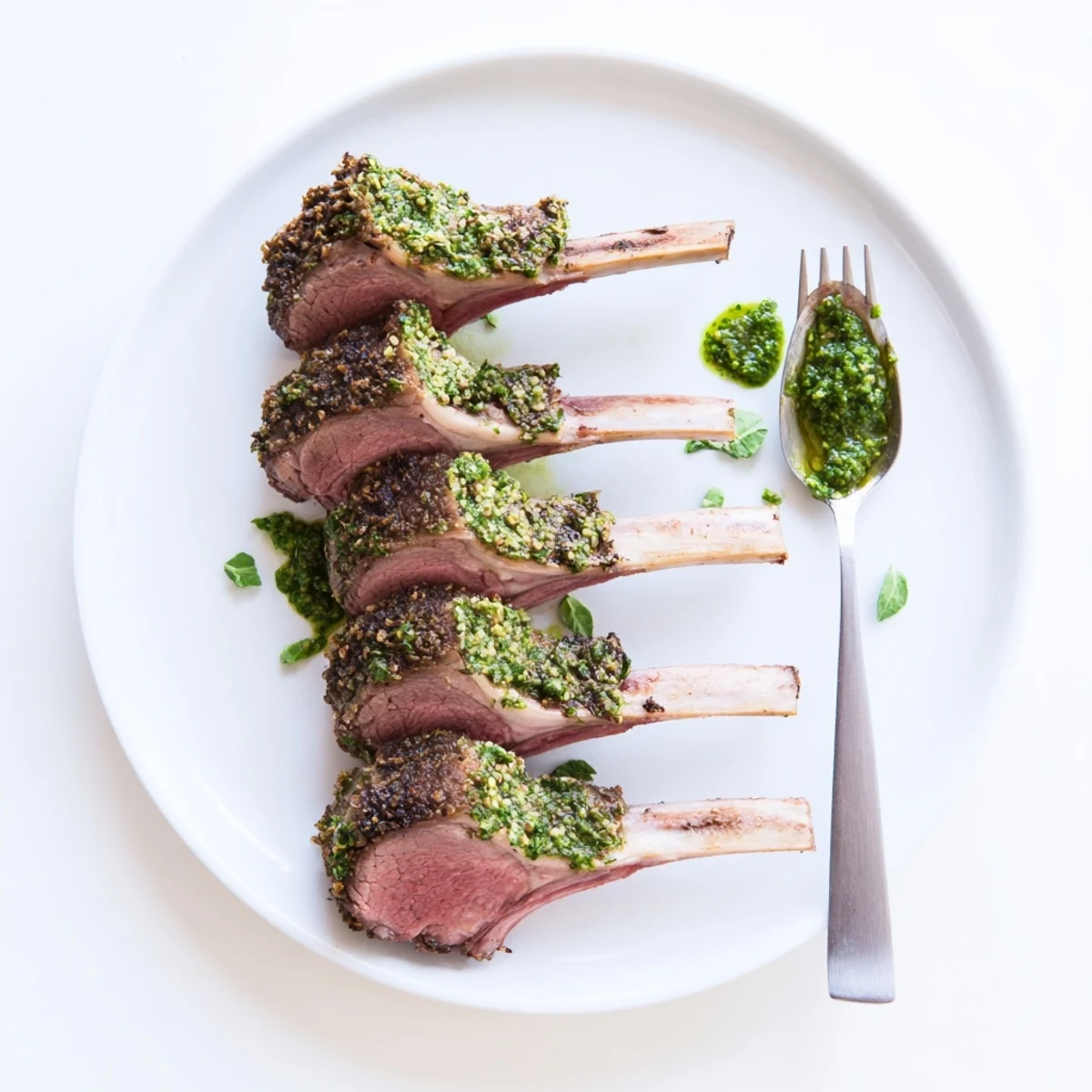 Juicy Garlic Herb Roasted Rack of Lamb with Mint Sauce plated with roasted potatoes and a green salad.