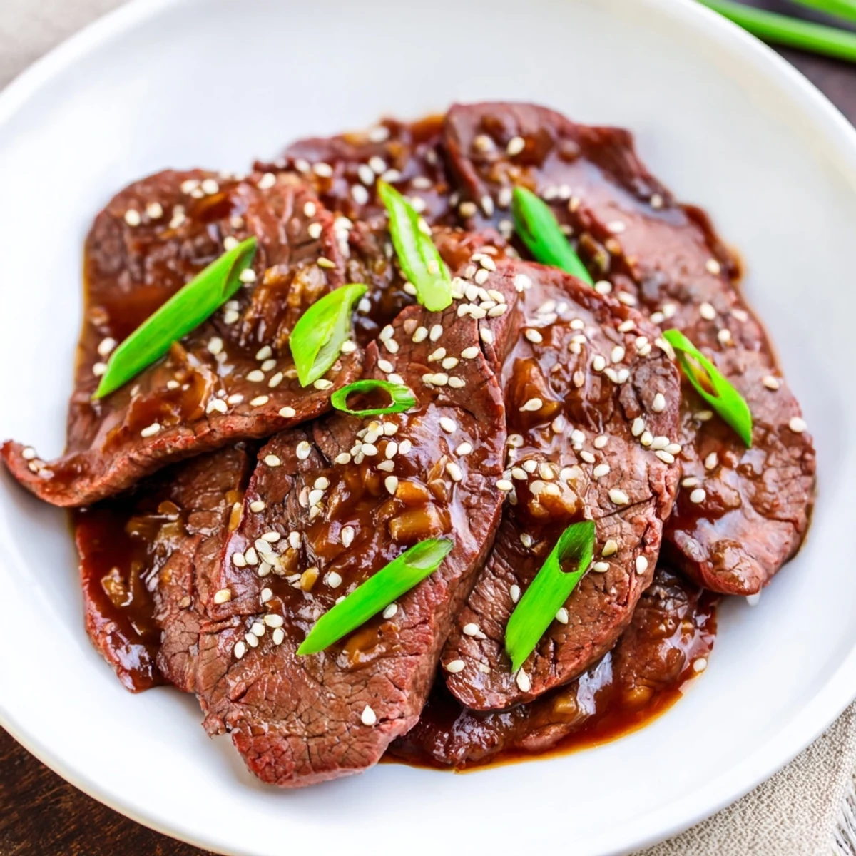 Ultimate Slow Cooker Mongolian Beef is served family-style in a bowl with glossy sauce, garlic, and ginger notes.