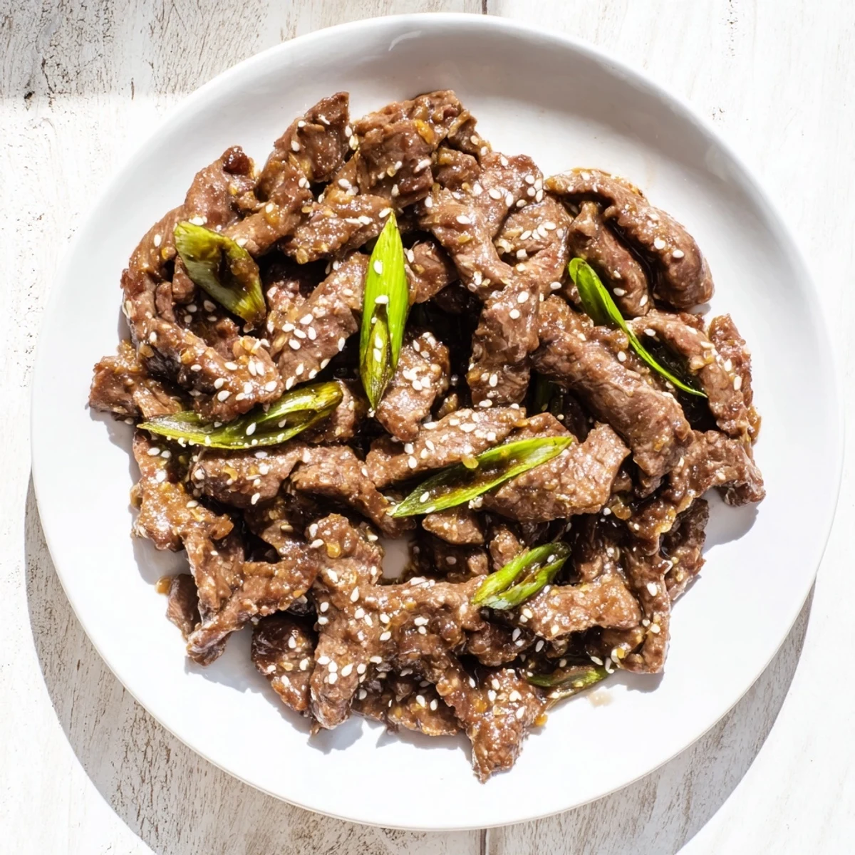 Tender Ultimate Slow Cooker Mongolian Beef is served steaming over jasmine rice with green onions and toasted sesame seeds