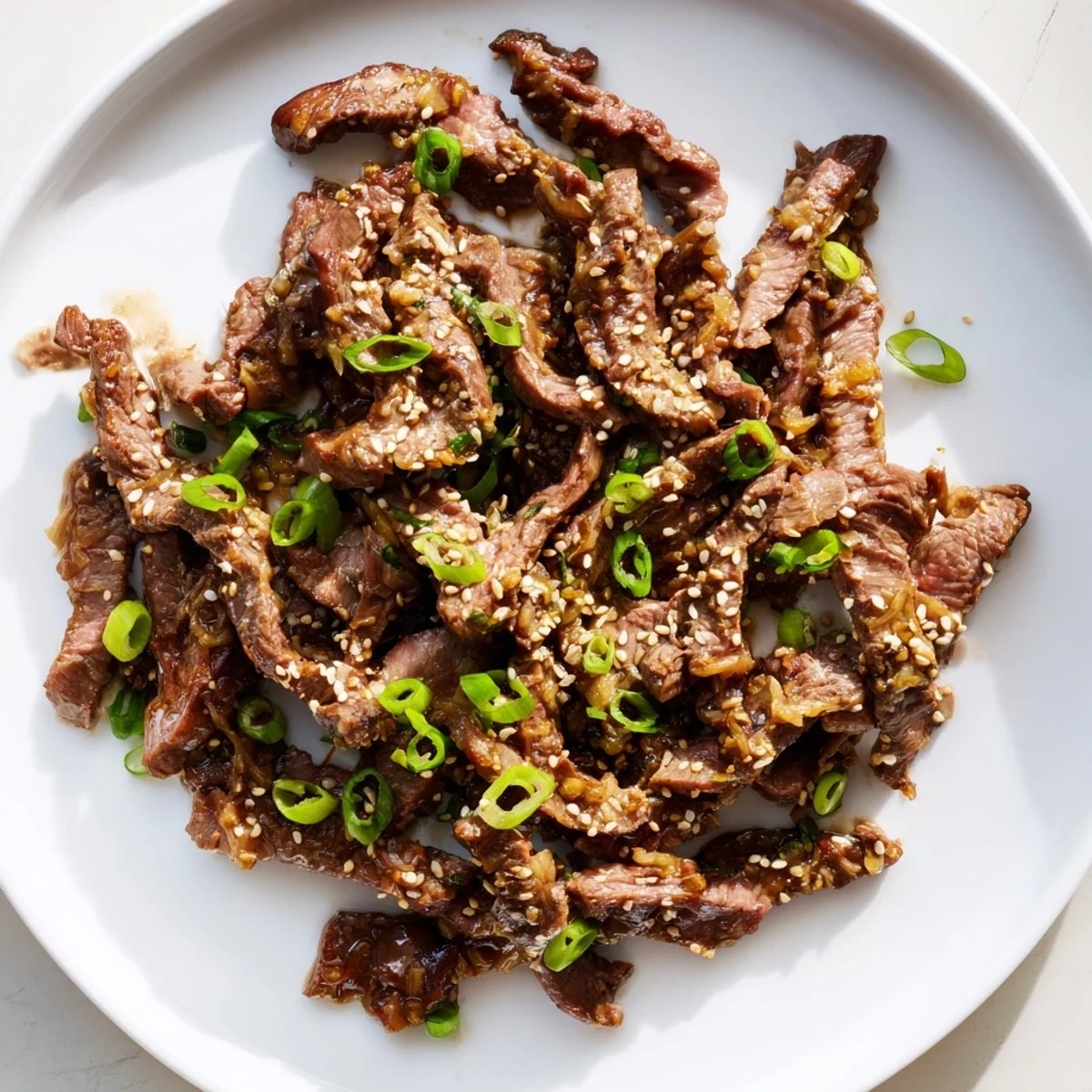 Ultimate Slow Cooker Mongolian Beef features beef strips bathed in a rich soy-garlic-ginger sauce, garnished with green onions and sesame seeds