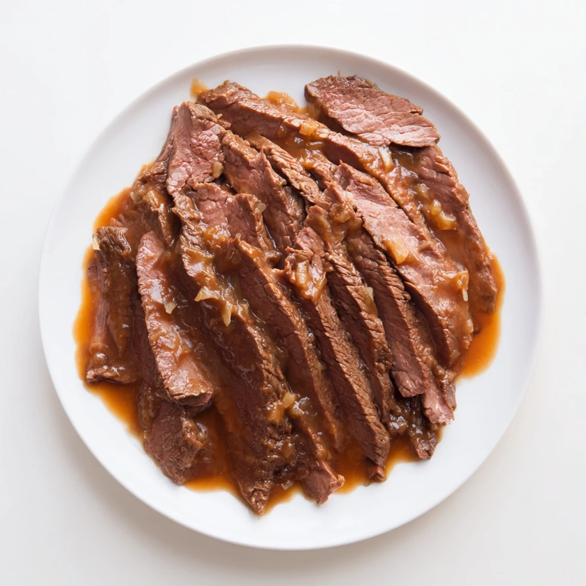 Fragrant garlicky sauce glistens on Ultimate Slow Cooker Mongolian Beef in a ceramic bowl, ready to be served hot.