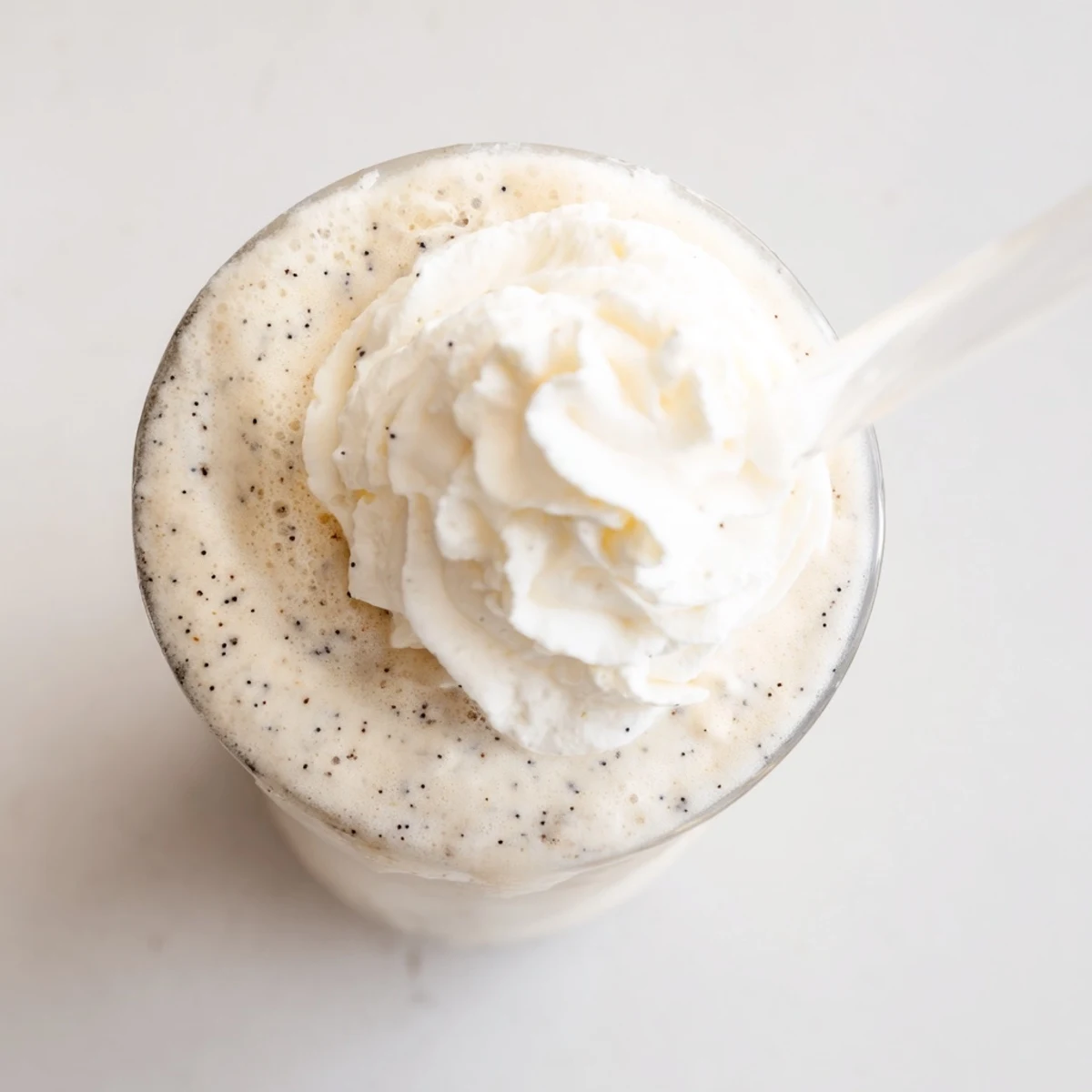 Homemade Vanilla Bean Frappuccino poured into glasses with visible vanilla bean specks and a frothy texture.