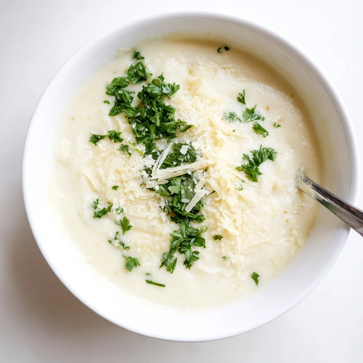Steaming bowl of Asiago Roasted Garlic Cauliflower Soup paired with crusty bread on the side.