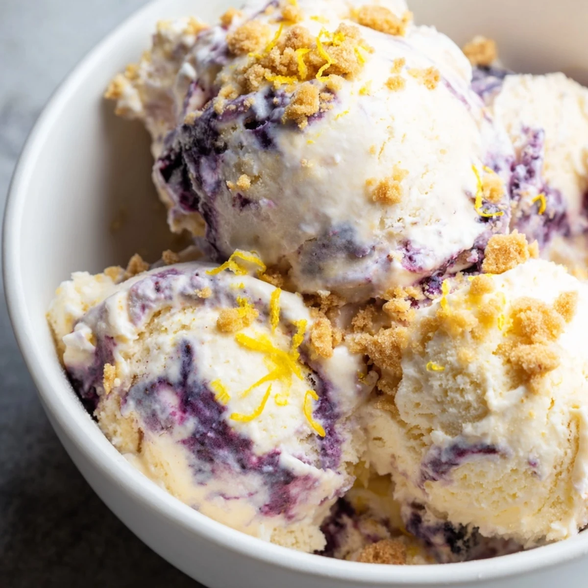 Lemon Blueberry Cheesecake Ice Cream served in a rustic ceramic dish, featuring a ribbon of blueberry sauce.