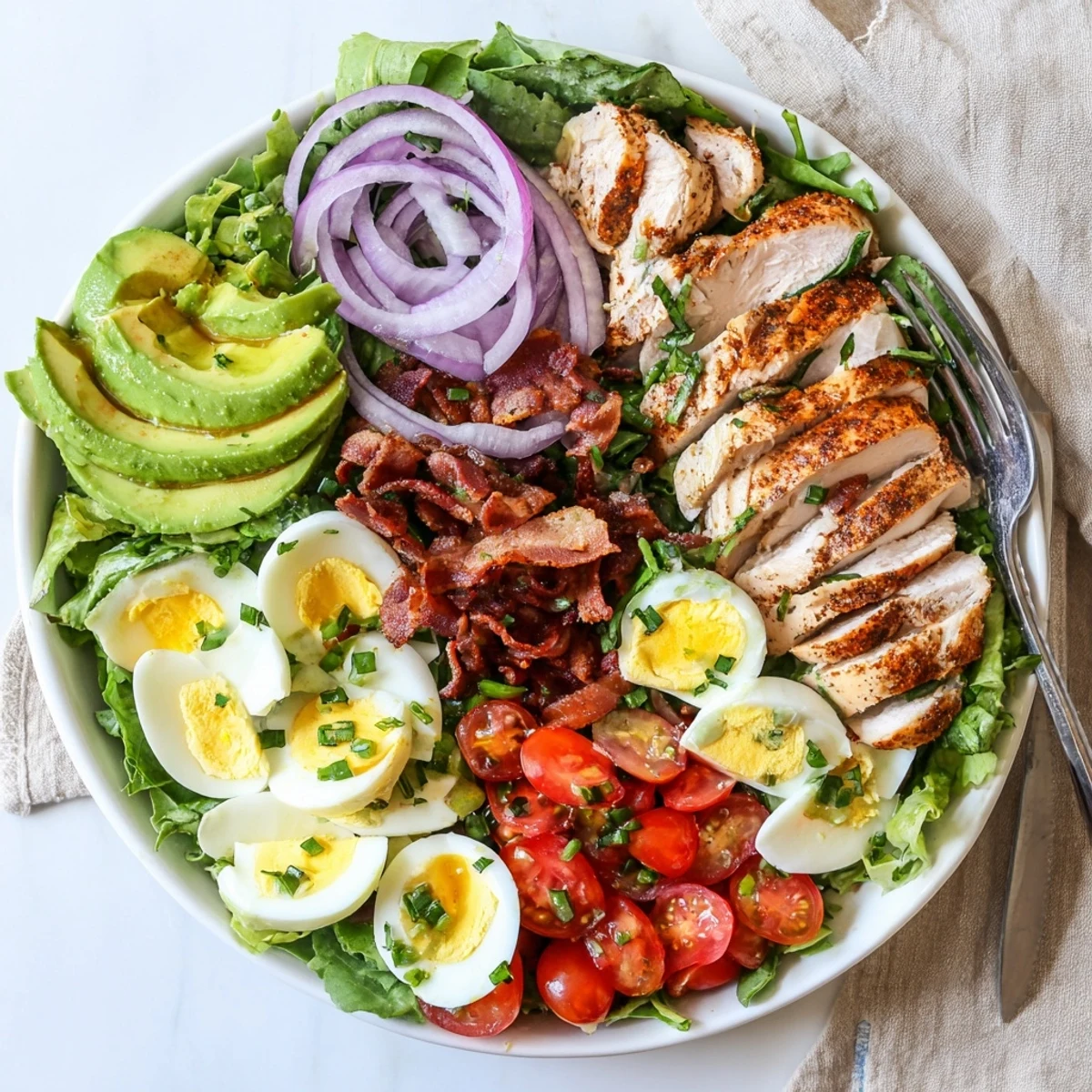 Close-up of the Paleo Grilled Chicken Cobb Salad With Honey Dijon Dressing showcasing hard-boiled eggs and cherry tomatoes on a platter.