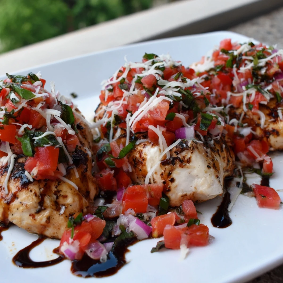 Italian-style Bruschetta Chicken drizzled with balsamic glaze and garnished with fragrant fresh basil