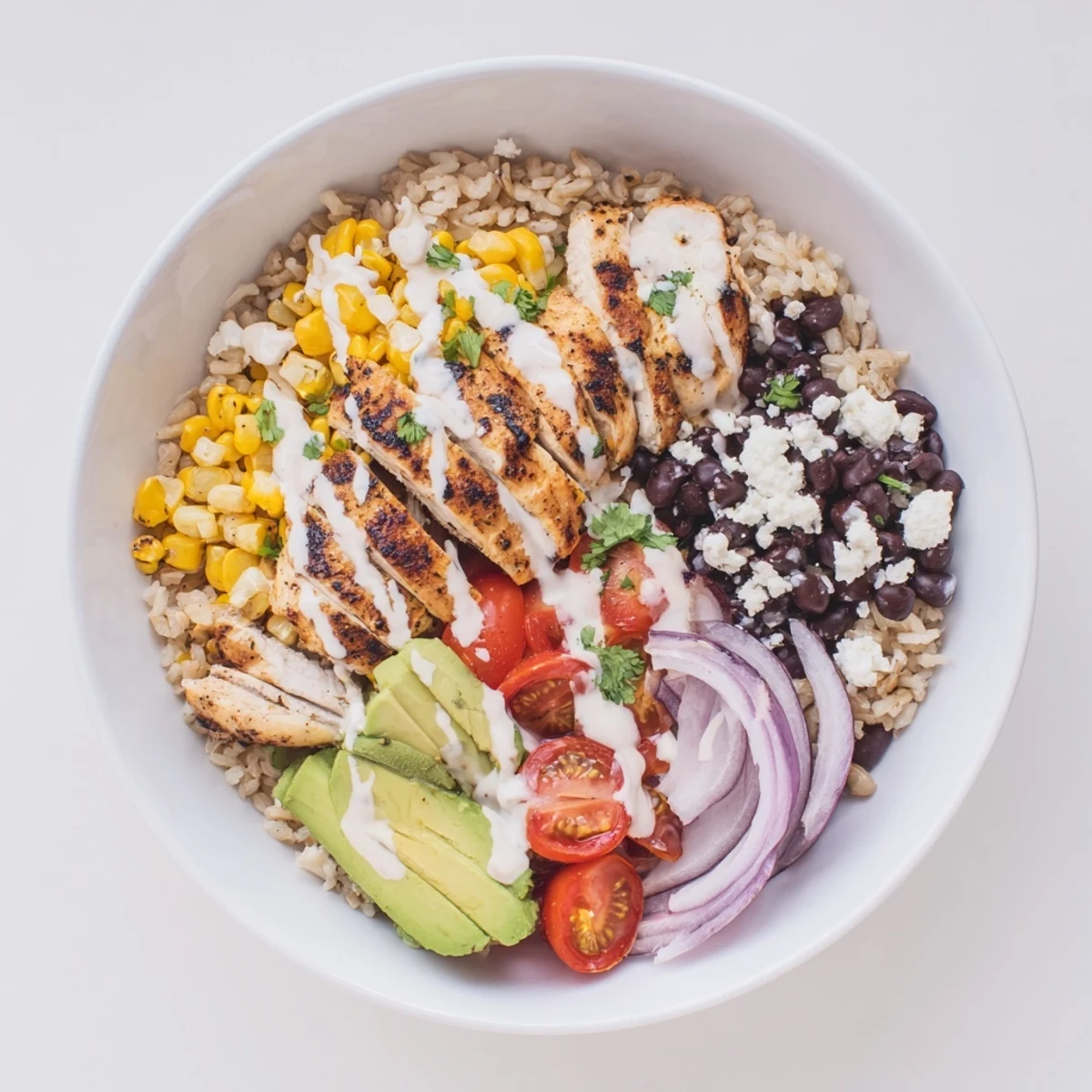 Sliced grilled chicken tops this vibrant protein packed street corn chicken bowl featuring corn, beans, tomatoes, and zesty yogurt dressing