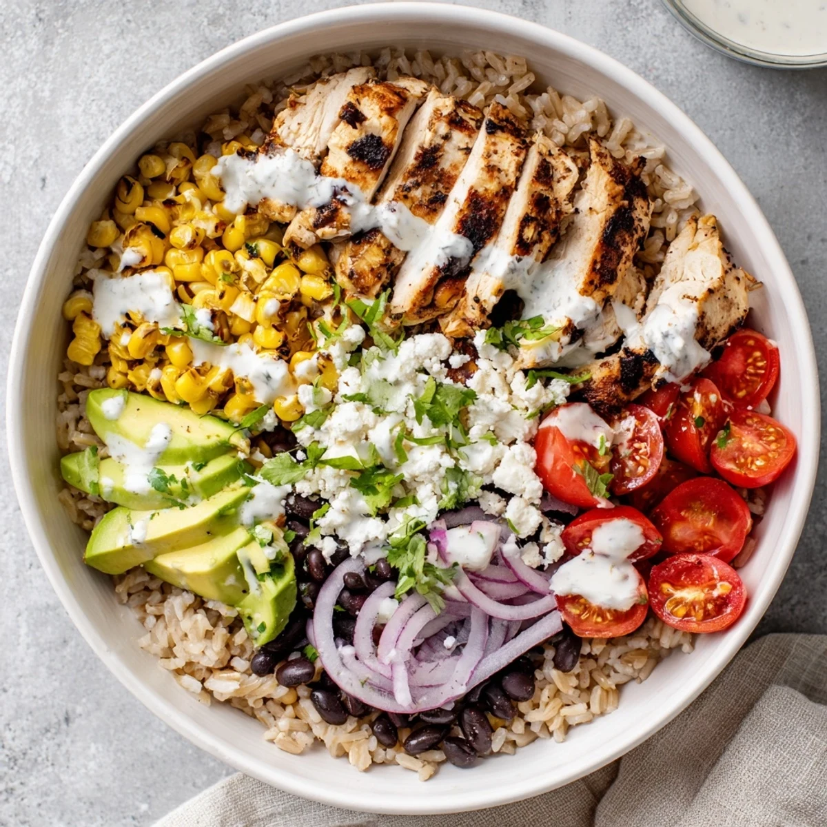 Hearty protein packed street corn chicken bowl layered with spiced chicken, cotija corn, fresh avocado, black beans, and cilantro garnish