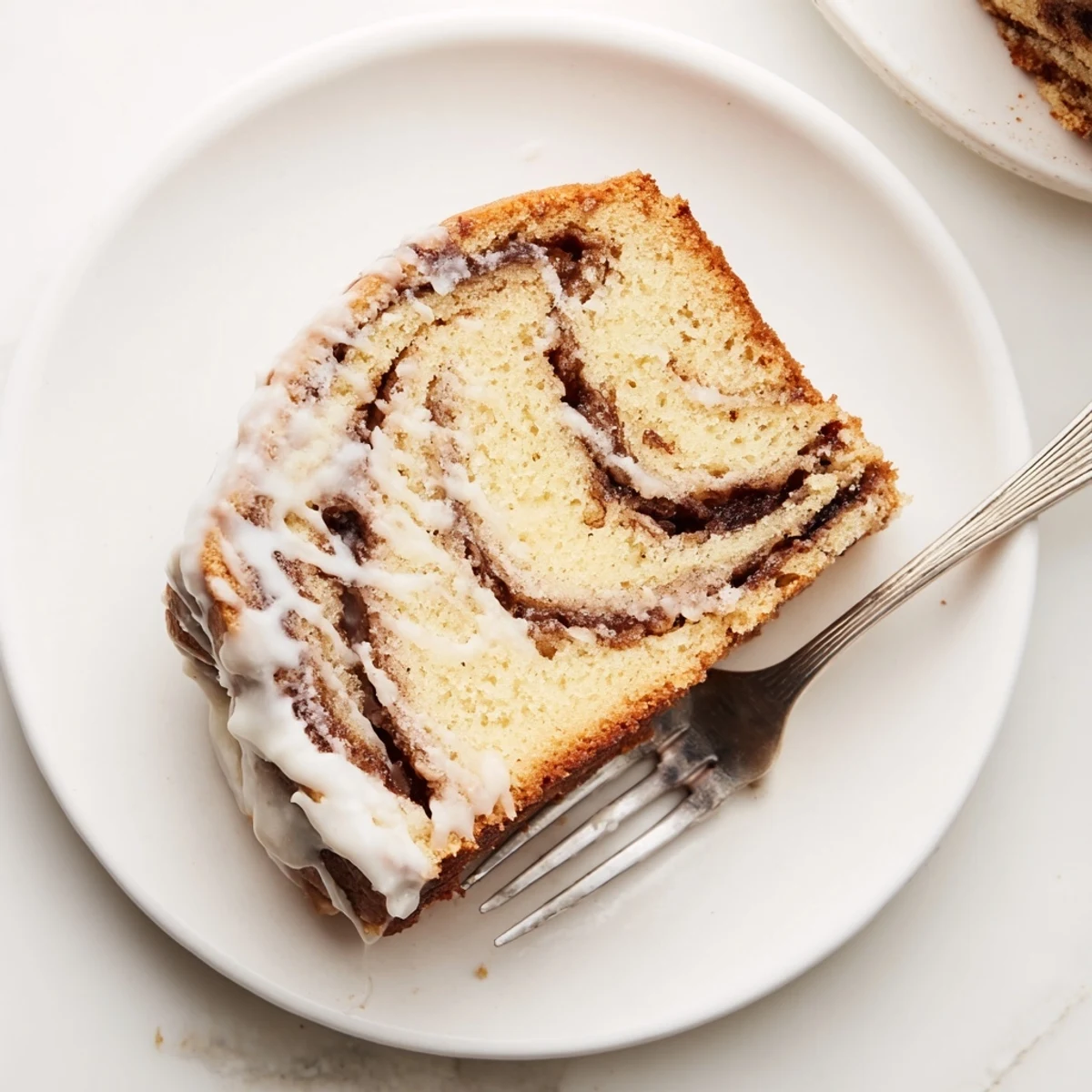 Golden cinnamon roll cake with marbled brown sugar swirls and creamy white vanilla glaze drizzled over the top