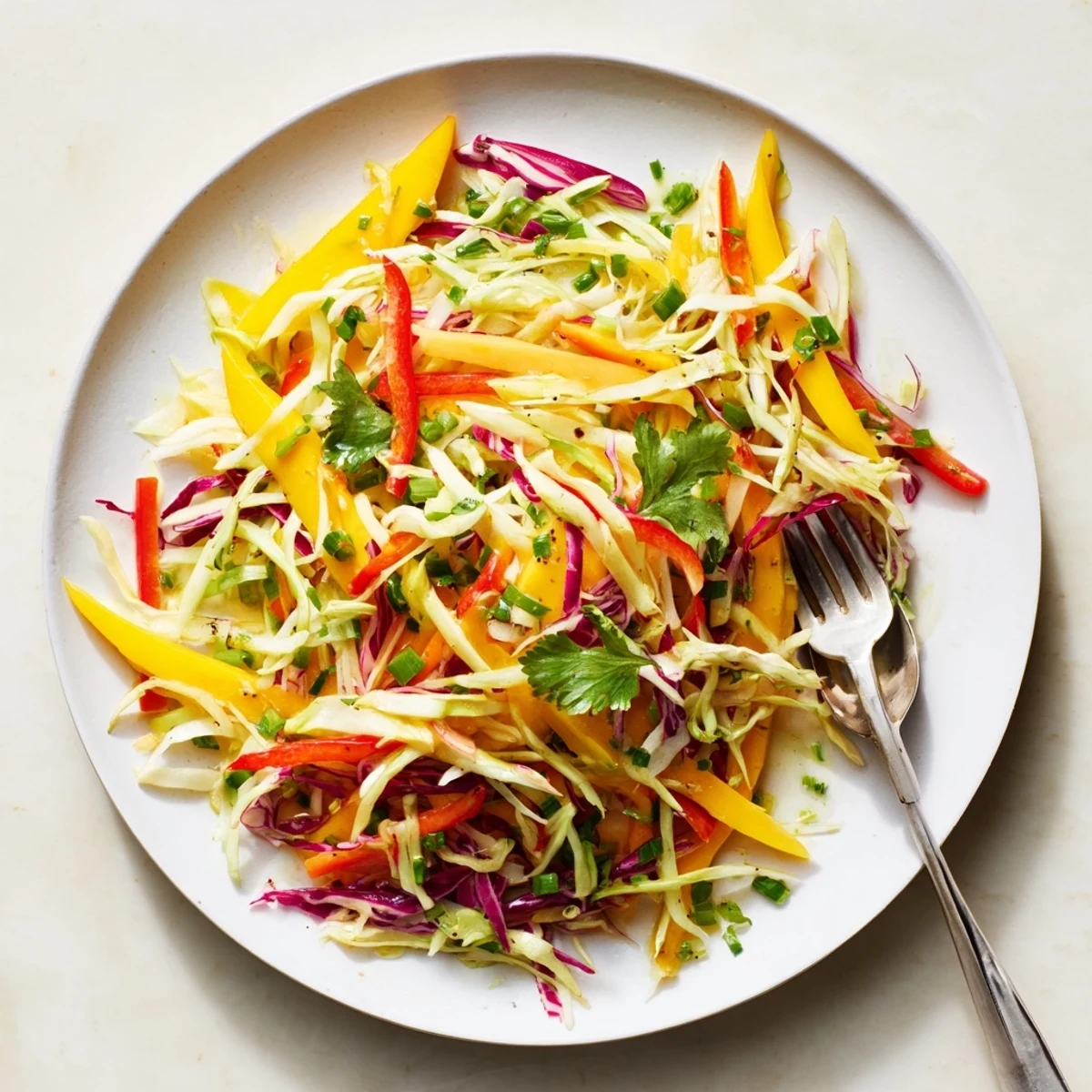 Colorful mango slaw bowl with shredded cabbage, julienned vegetables, and fresh cilantro garnish