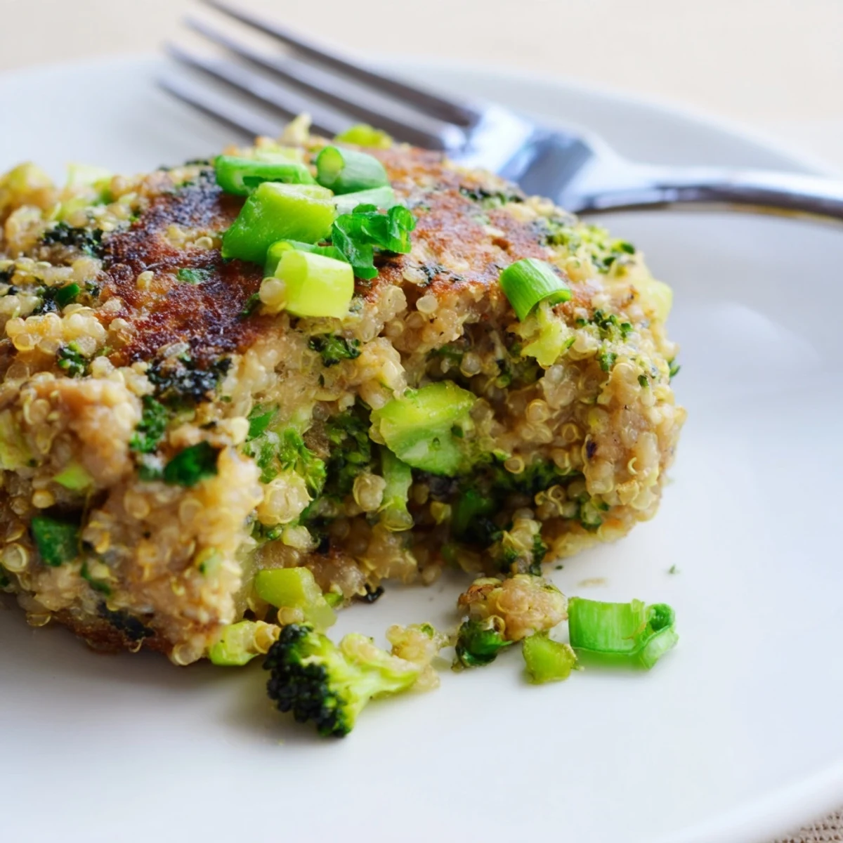 Golden brown turkey broccoli and quinoa burgers sizzling in a skillet with fresh green onions