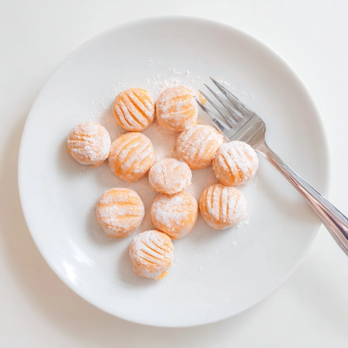 Orange cream cheese mints arranged on a white serving plate with fork impressions