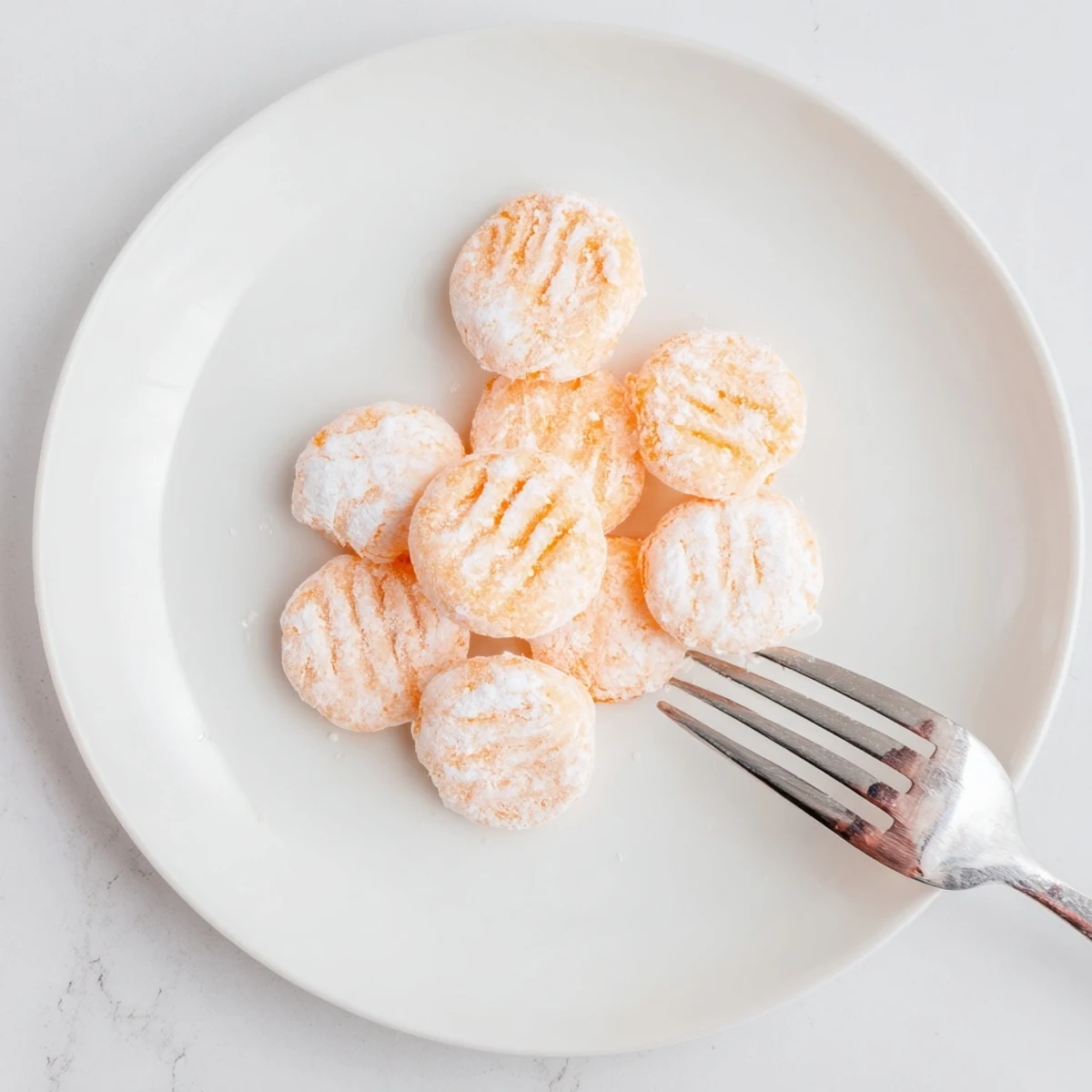 Homemade orange cream cheese mints displayed in a decorative glass bowl for parties