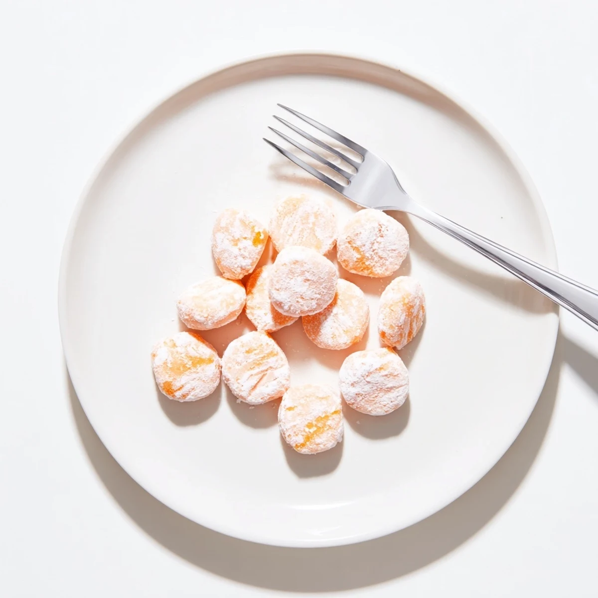 Creamy orange mints dusted with powdered sugar on a wooden serving board