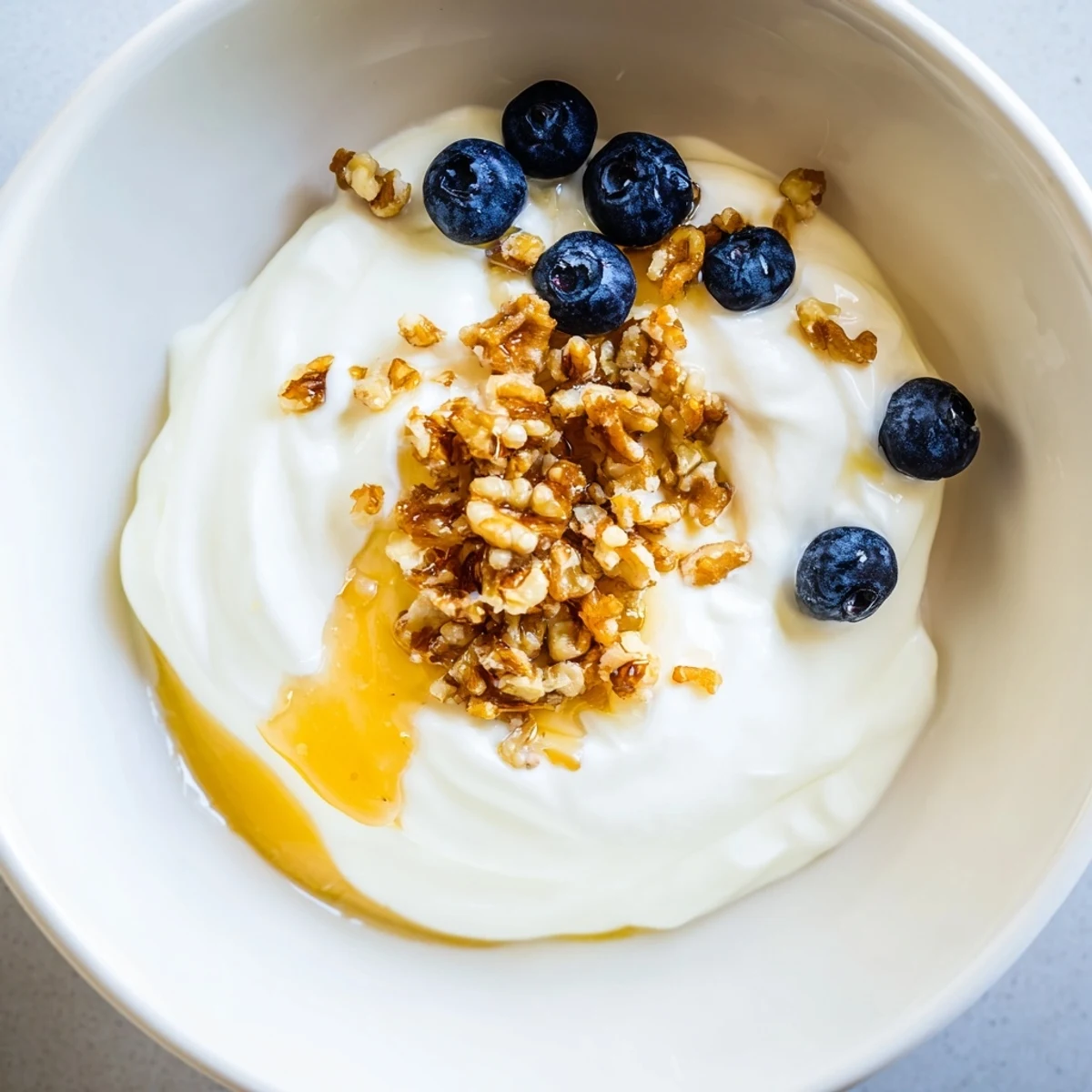 Thick white Greek yogurt spoon dripping into serving bowl with cheesecloth strainer