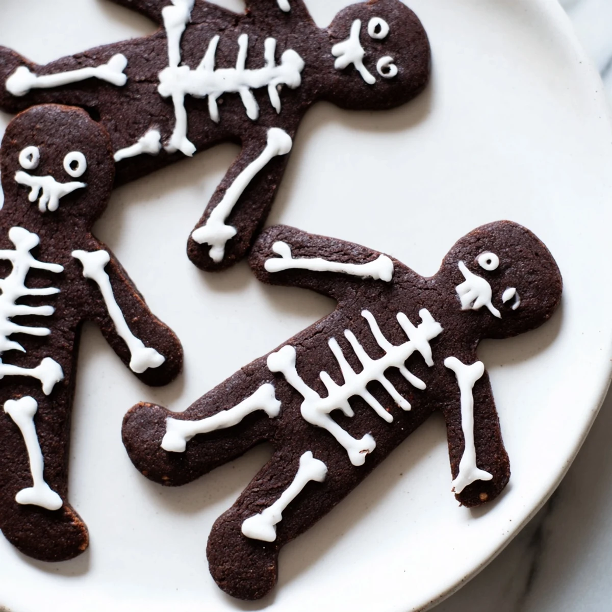 Dark cocoa Chocolate Cinnamon Skeleton Cookies piped with spooky royal icing skeleton designs