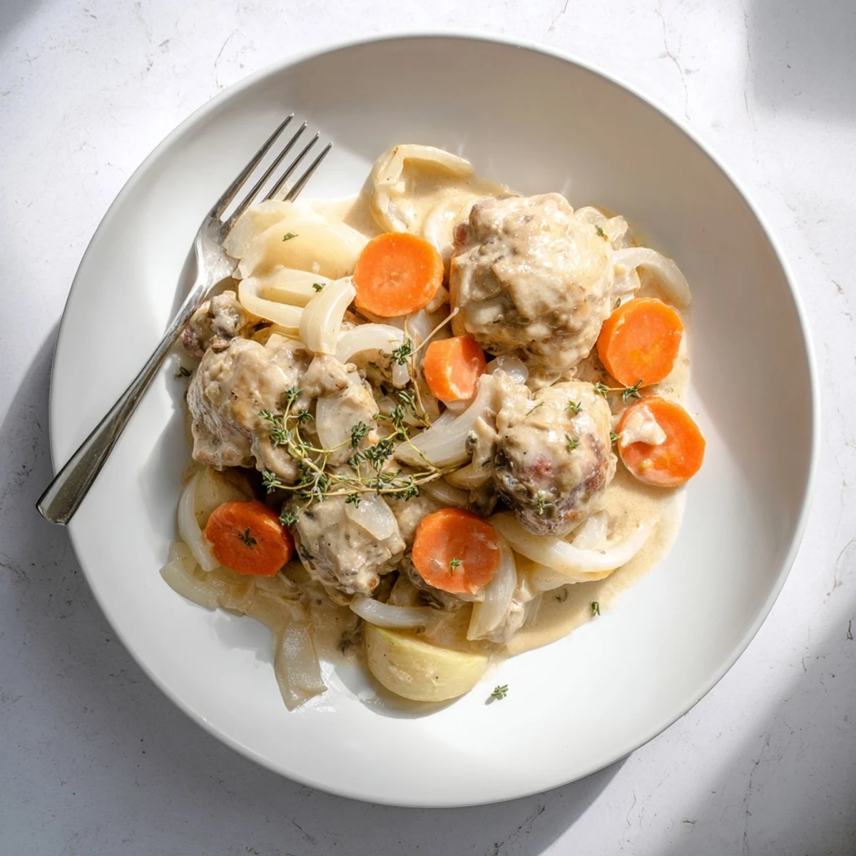 Rustic French chicken casserole à la Normande plated with braised chicken thighs, caramelized apple slices, and velvety cream sauce