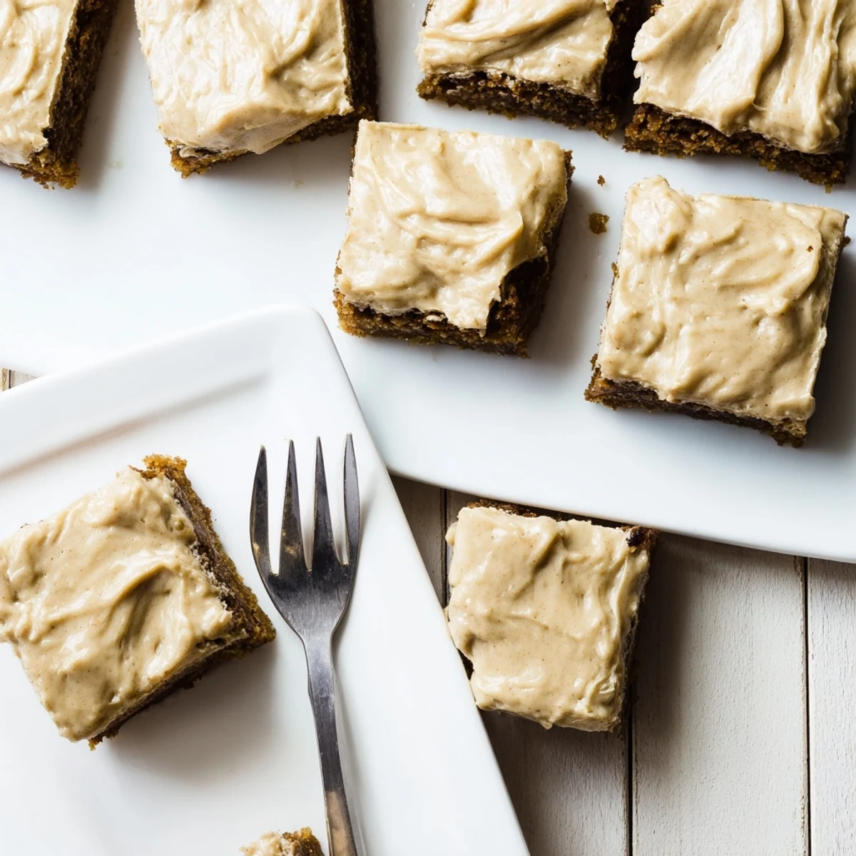 Thick banana bread brownies with creamy brown butter frosting on a white plate