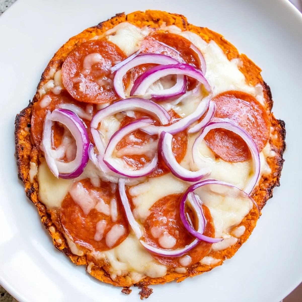 Sliced pepperoni hot honey pizza featuring orange sweet potato base and bubbly cheese topping