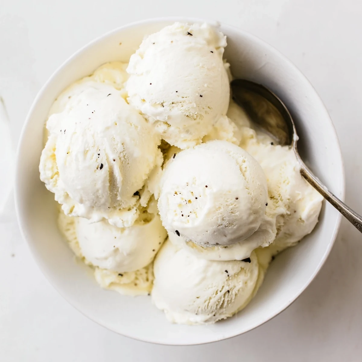 Homemade vanilla ice cream with fresh berries and mint garnish on a white plate