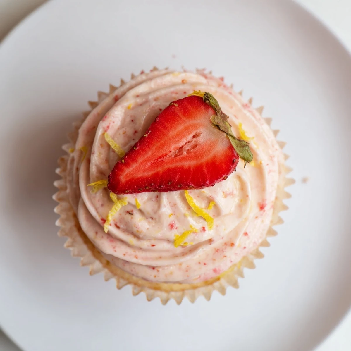 Light and fluffy strawberry lemonade cupcakes garnished with fresh strawberry slices and zest on a baking rack