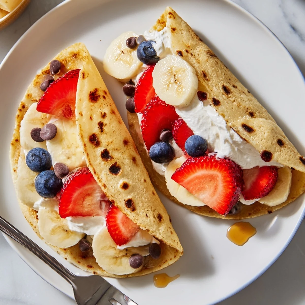 Golden fluffy pancake tacos stuffed with fresh berries, whipped cream, and maple syrup drizzle
